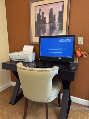A computer with a blue screen is on a desk with a white chair.